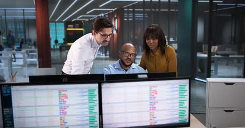 Young Analyst And Team Using Computers, Reviewing Data Spreadsheets, And Codi Stock Photos