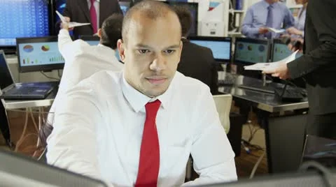 Young and ambitious male stock market trader hard at work in a busy office Stock Footage