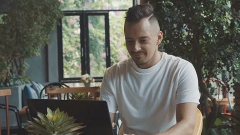 Young and ambitious writer is working on his book using laptop computer in cafe. Stock Footage 76288442