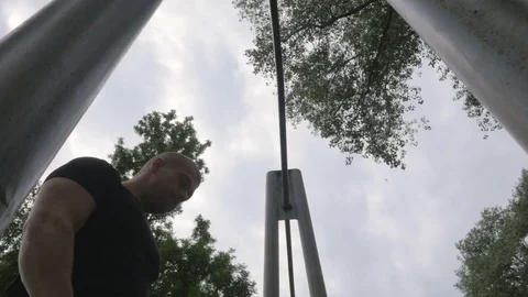 Young and athletic man doing pull-ups outdoors elements of workout. Video stock 84003188