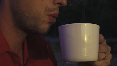 A young and attractive man drinks hot tea or coffee, in profile, close-up Stock Footage 81179649