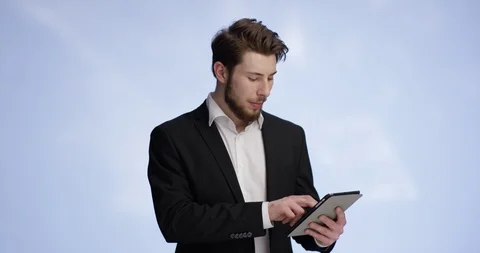 Young and attractive man typing on a tablet and smiling into the camera Stock Footage 99307833