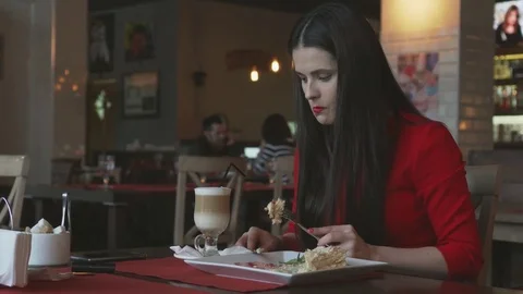 The young and beautiful girl eats puff cake at restaurant and drinks coffee Stock Footage 85328802