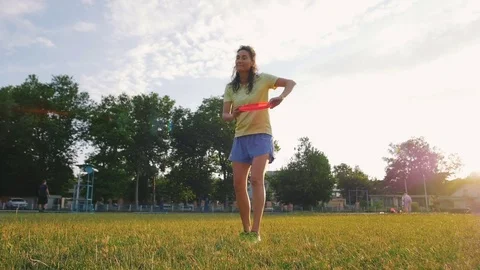 Young and beautiful woman playing frisbee in the park, slow motion Stock Footage