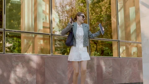 The young and cheerful student dancing outside. Woman in a white dress and Stock Footage 213009158