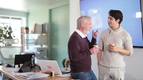Young and elderly men colleagues drinking coffee in office Stock Footage 341785353