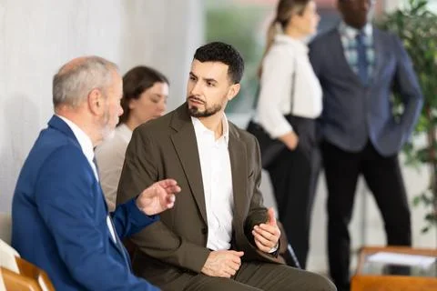 Young and elderly men talking while waiting in job interview queue Foto stock