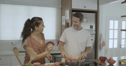 Young and friendly couple cooking together and the husband tastes the food. Stock Footage 232425678