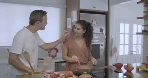 Young and friendly man and woman cook in a modern kitchen and wife tastes food. Stock Footage 232417874