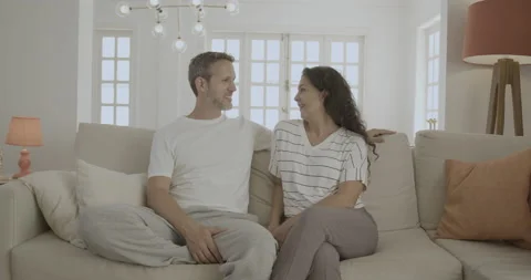 Young and friendly man and woman talk and kiss on the sofa. Stock Footage 232418108