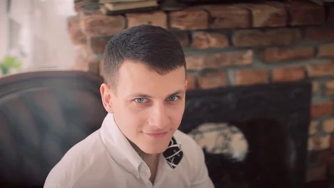 Young and handsome groom in white shirt with bowtie sitting on armchair Stock Footage 74138779