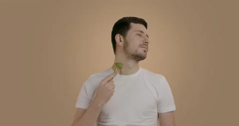 Young and handsome man with clean and fresh skin massaging the neck area using a Stock Footage 227012289