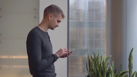 The young and handsome man writes messages on phone Stock Footage 81853896