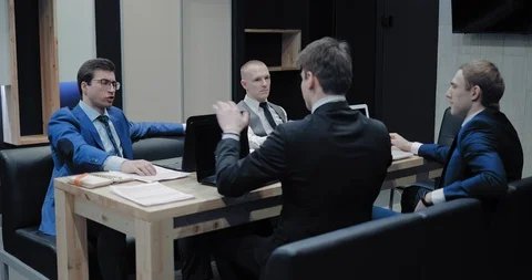 Young and handsome men sit in a meeting at a table with laptops. Colleagues Video stock 102477856