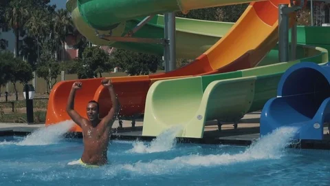 Young and happy couple having fun watersliding into the pool. Slow motion 1080p Stock Footage 80884310