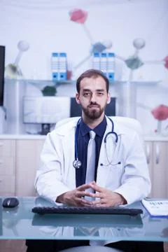 Young and inteligent doctor in his cabinet wearing a white coat and his Stock Photos