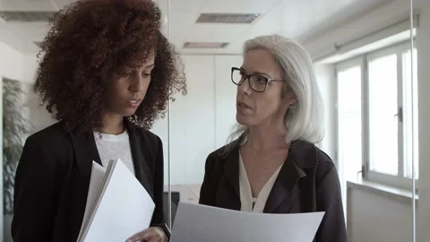 Young and middle aged colleagues reviewing and discussing paper Stock Footage 137515568