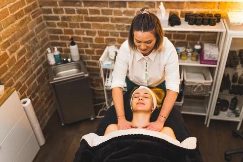 Young and nice-looking blond woman getting a massage on her chest at the salon Stock Photos