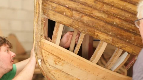 Young and old boat builders working together fitting oak ribs Stock Footage 339019273