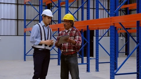 Young and old engineers talk about inventory storage system in new warehouse. Stock Footage 125725095
