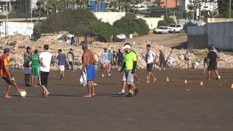 Young and old men play football (soccer) on beach in Casablanca, Morocco Video stock 71490837