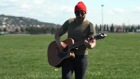 Young and positive talented Middle Eastern musician enjoying playing guitar  Stock Footage 240497595