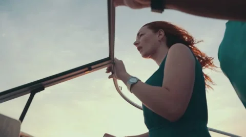 Young and pretty red hair girl on motor boat. Summer windy evening. Dress Stock Footage