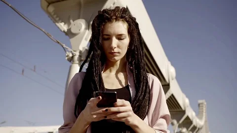 Young and stylish woman with dreadlocks correspond with friends on a mobile phon Stock Footage