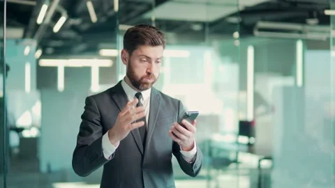 Young angry annoyed and displeased business man in office using smart mobile  Stock Footage