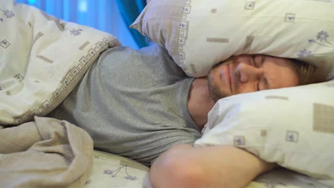 Young angry man trying to sleep covering ears with pillow. Noisy neighbors Stock Footage 145613022