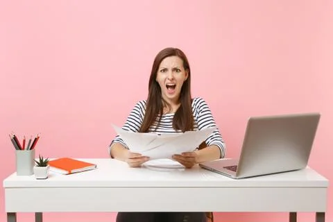 Young angry woman having problem screaming holding paper documents, work on Stock Photos