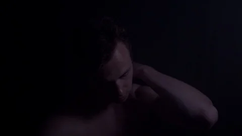 Young anxious man sitting in a dark being scared and nervous looking into Stock Footage 112030342