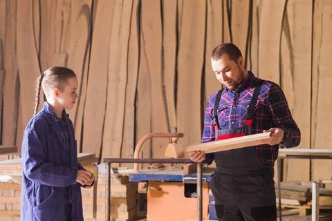 Young apprentice learning to work at carpentry shop Young teen boy in blue... Stock Photos