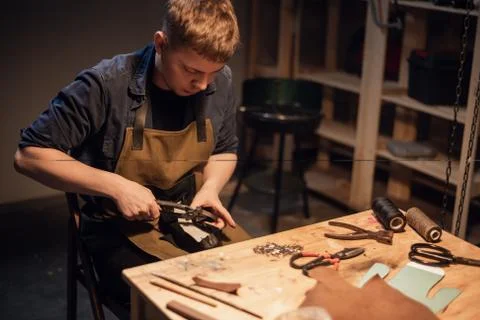 A young apprentice makes blanks for the production of shoes in the workshop. Stock Photos