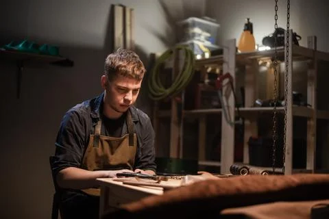 A young apprentice makes blanks for the production of shoes in the workshop. Stock Photos