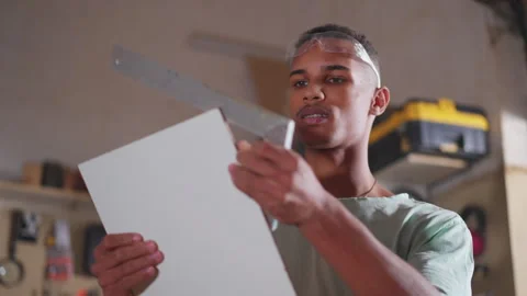 Young Apprentice Measuring and Sawing Wood in Carpentry Workshop Video stock 246792354