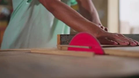 Young Apprentice Measuring and Sawing Wood in Carpentry Workshop 库存照片