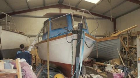 Young apprentice shipwright boards fiberglass boat to inspect gunwale Stock Footage 234178411