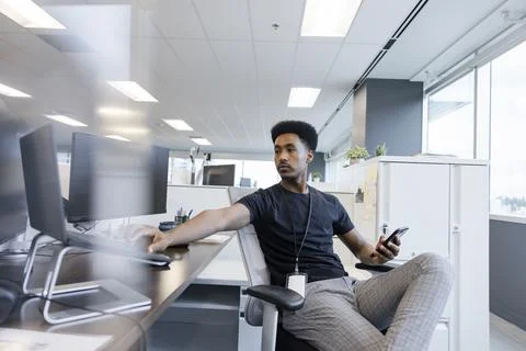Young apprentice typing on laptop at desk in coworking space Stock Photos