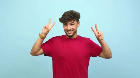 Young arab man fun and happy, positive and natural, doing a gesture of victory, Video stock 138664983