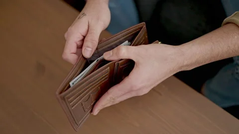 Young arab man holding dollars on wallet sitting on sofa at home Stock Footage 233419077