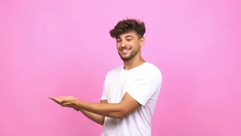 Young arab man holding something with hands, showing a product, smiling and Stock Footage 138664148
