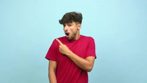 Young arab man pointing to the side,  surprised and shocked presenting something Stock Footage 138665218
