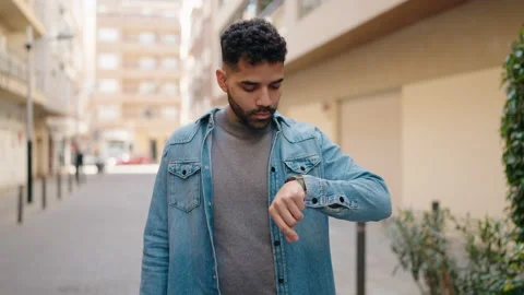 Young arab man with relaxed expression looking watch at street Video stock 171791856