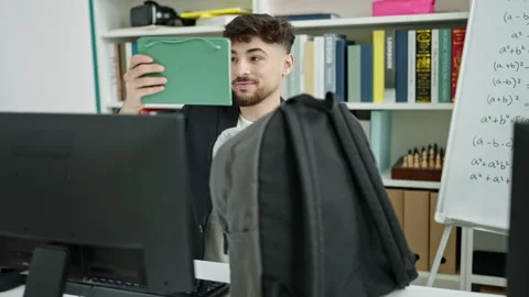 Young arab man student using computer eating banana at university classroom 스톡 동영상 241144916