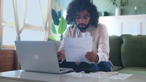 Young Arabian man uses laptop to fill out financial or tax returns Stock Footage