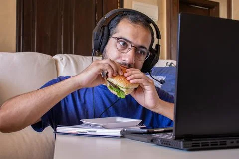 Young arabic man eating while working and  at home Stock Photos