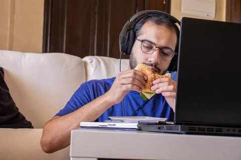Young arabic man eating while working and  at home Stock Photos