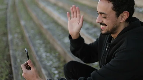 Young Arabic man having video chat outside, waving hand Stock Footage 103031292