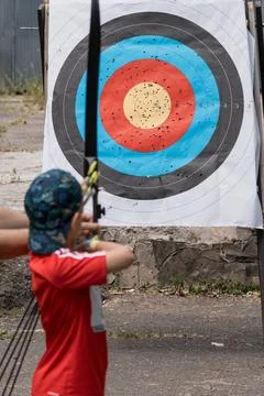 Young Archer Practicing Target Shooting Outdoors with Bow and Arrow, Red Sh.. Stock Photos